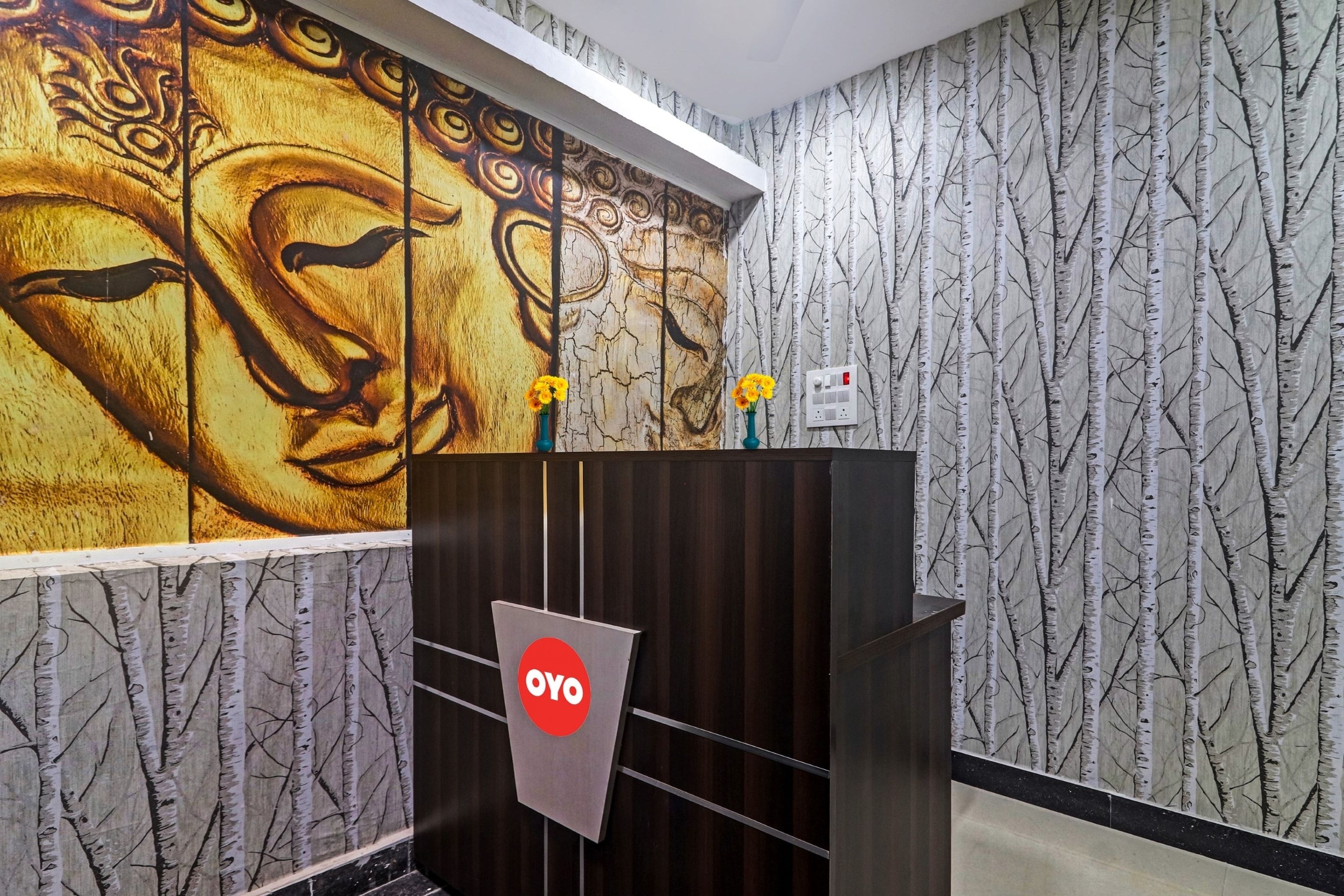 A reception area with a wooden desk, a wall mural, and a patterned wallpaper.