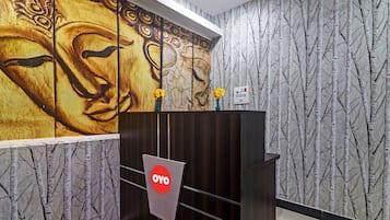 Un área de recepción con un escritorio de madera, un mural en la pared y un papel tapiz estampado.