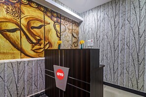 A reception area with a wooden desk, a wall mural, and a patterned wallpaper.