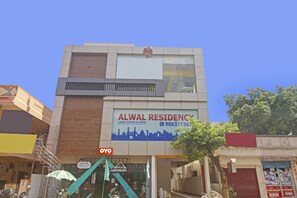 A building with a sign for Alwal Residency, indicating it offers luxury rooms or AC rooms.