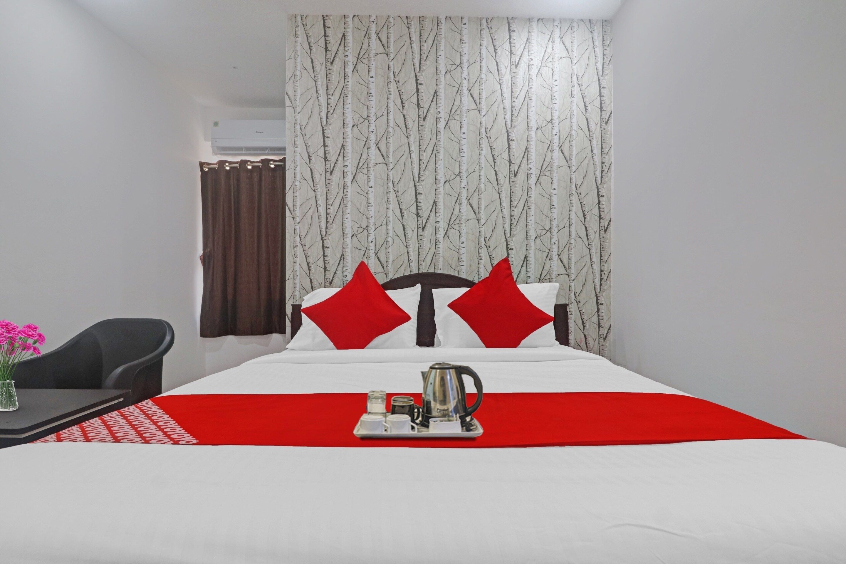 Habitación de hotel con una cama, una mesita de centro con un hervidor, una silla y una cortina.
