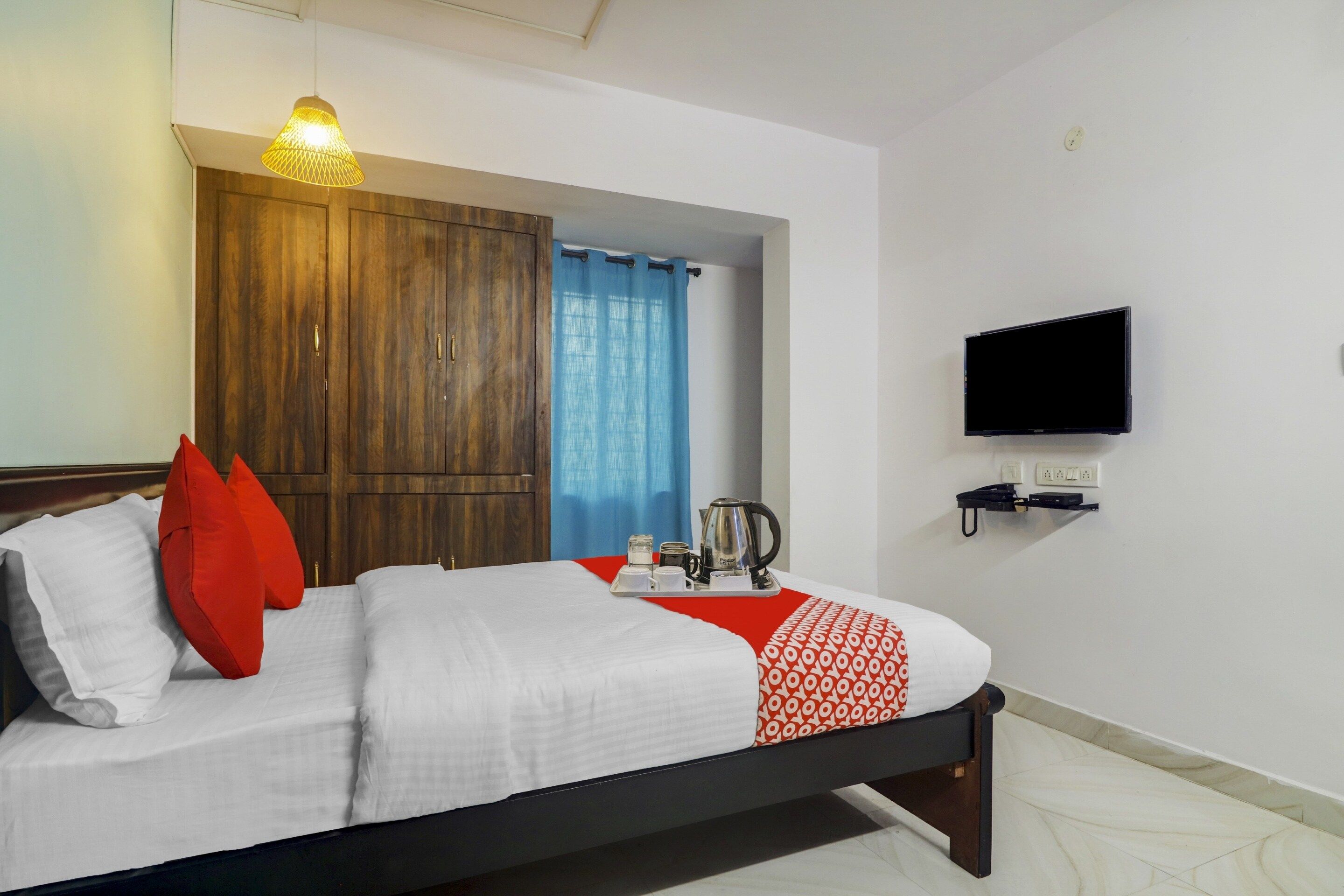 Une chambre d’hôtel avec un lit, un téléviseur fixé au mur et une armoire en bois.