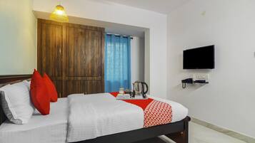 Une chambre d’hôtel avec un lit, un téléviseur fixé au mur et une armoire en bois.