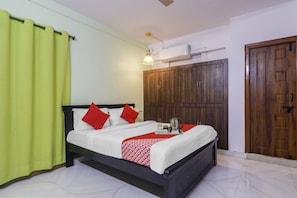 Habitación de hotel con cama, armario, ventilador de techo y ventana con cortinas.