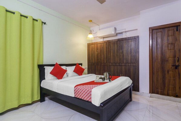 Habitación de hotel con cama, armario, ventilador de techo y ventana con cortinas.