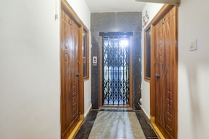 Un pasillo con puertas de madera y un portón metálico al final.
