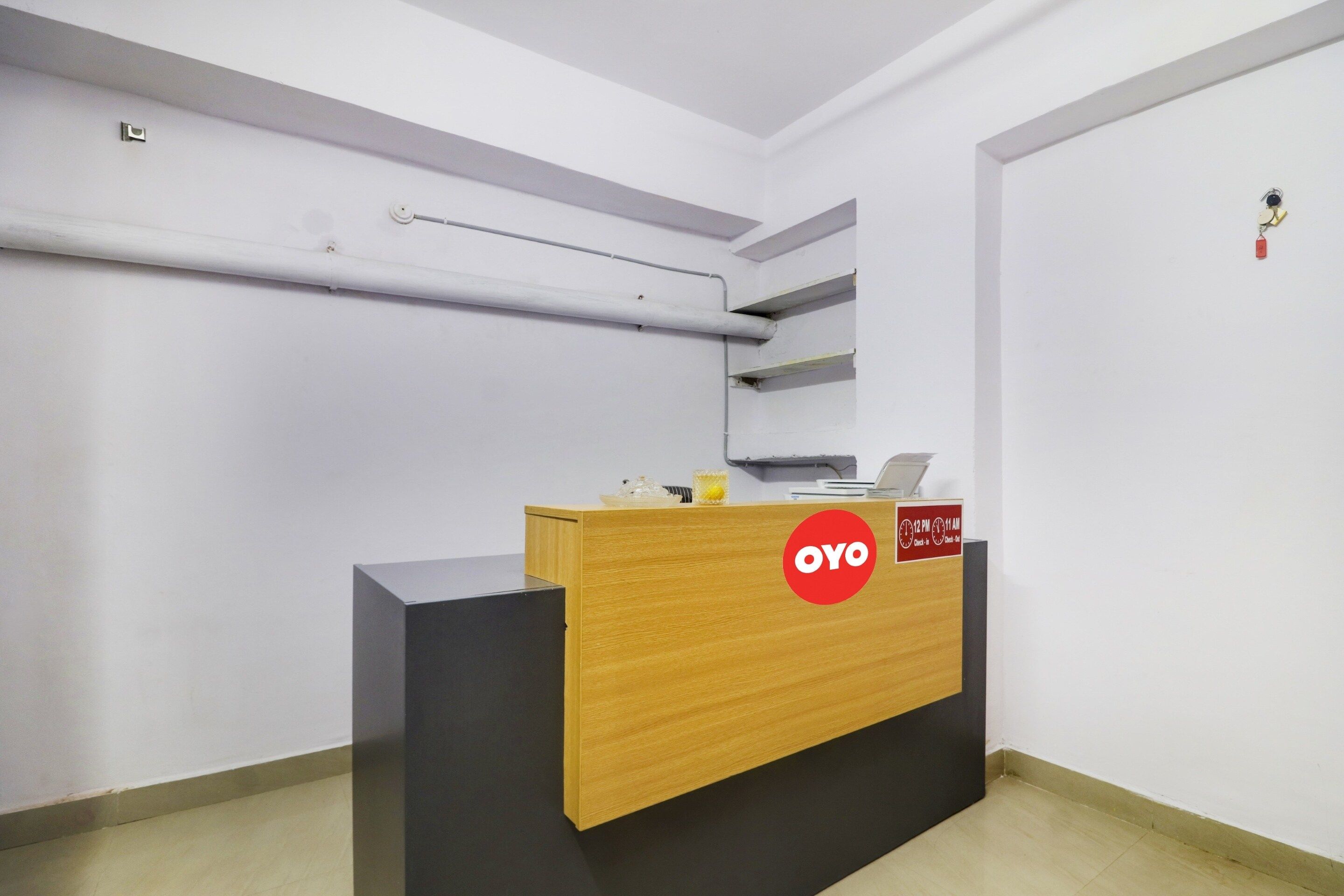 A reception desk with a wooden top and black base, a clock, and a sign indicating check-in and check-out times.