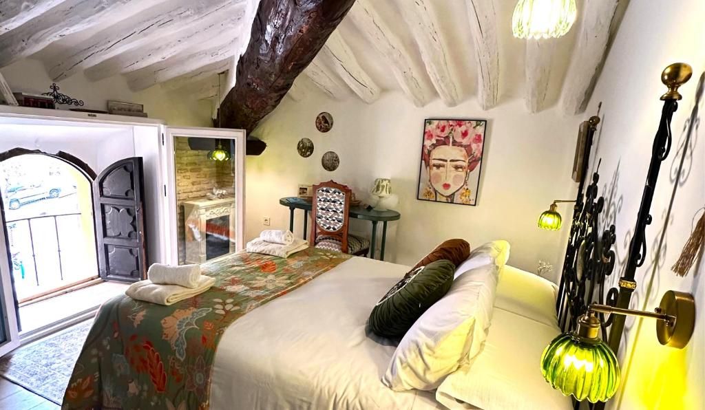A bedroom with a bed, a nightstand, a lamp, and a painting on the wall.