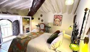 Een slaapkamer met een bed, nachtkastje, lamp en een schilderij aan de muur.