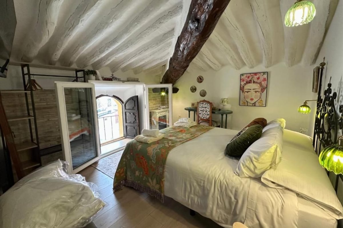 Een slaapkamer met een bed, een glazen deur naar een balkon en een houten plafond.