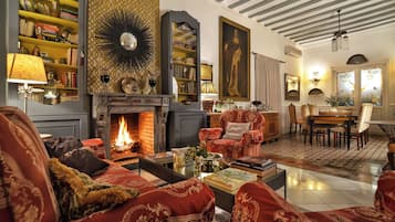 Un salon chaleureux avec une cheminée, des fauteuils confortables et une bibliothèque remplie de livres.