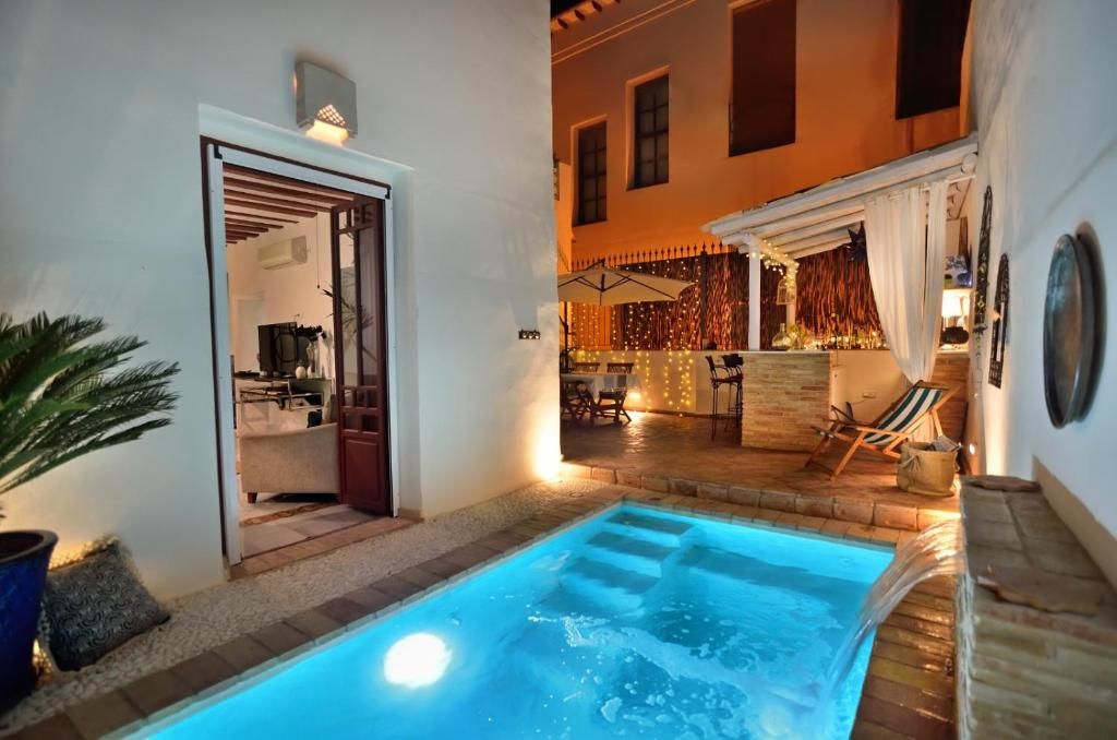 A pool area with a hot tub, outdoor seating, and a view of the interior.