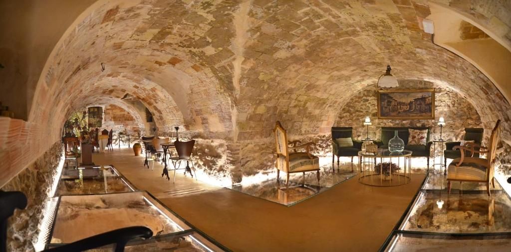 Un espace de restauration souterrain agrémenté d’arches en pierre, de tables, de chaises et d’un comptoir de bar.