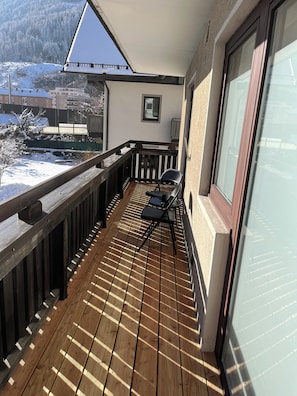 Ein Balkon mit Holzboden, einem Stuhl und einem Fenster mit Blick auf eine verschneite Landschaft.