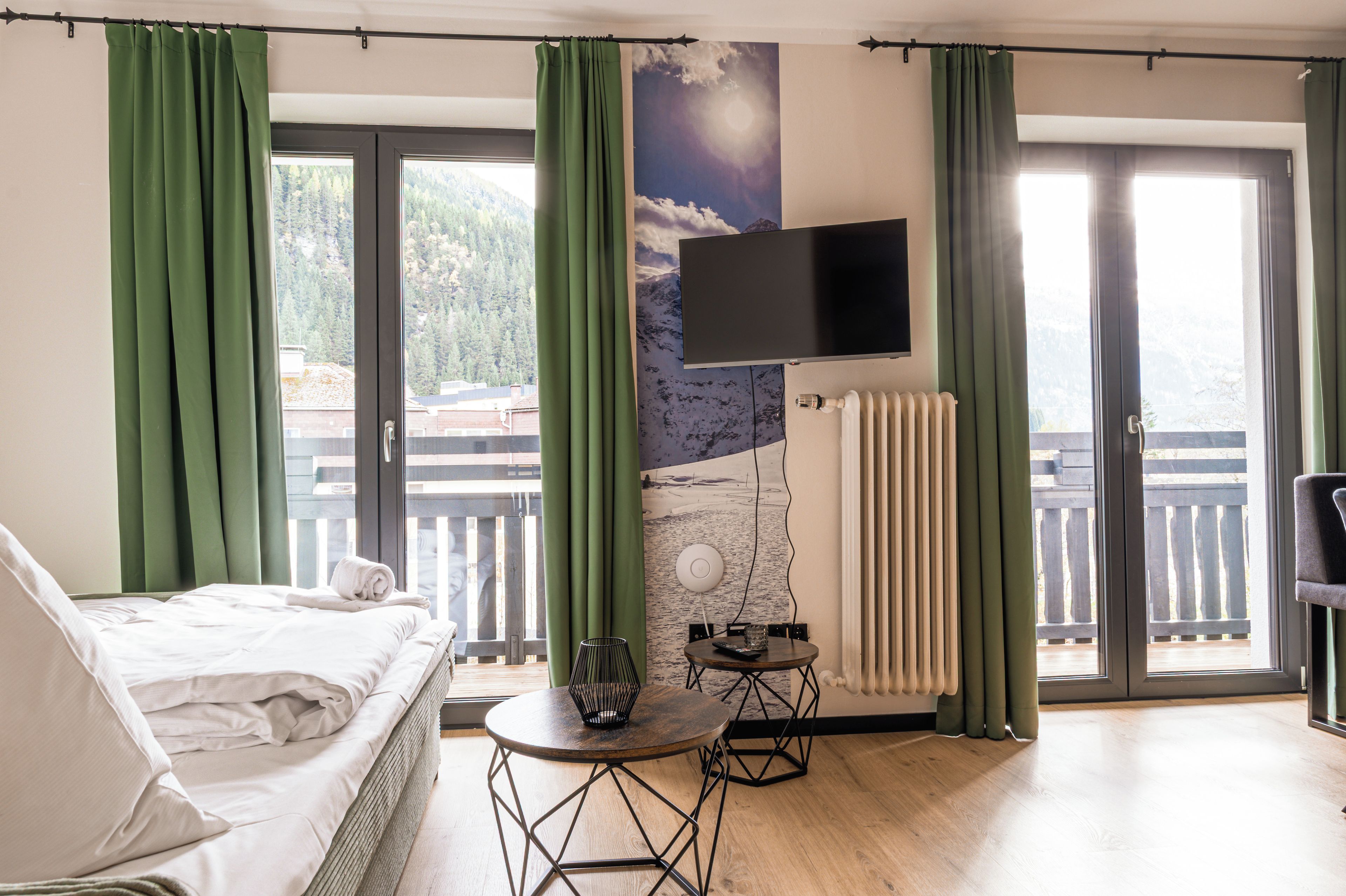 Une chambre d’hôtel avec un lit, une table, un t éléviseur fixé au mur et une vue sur l’extérieur par les fenêtres.