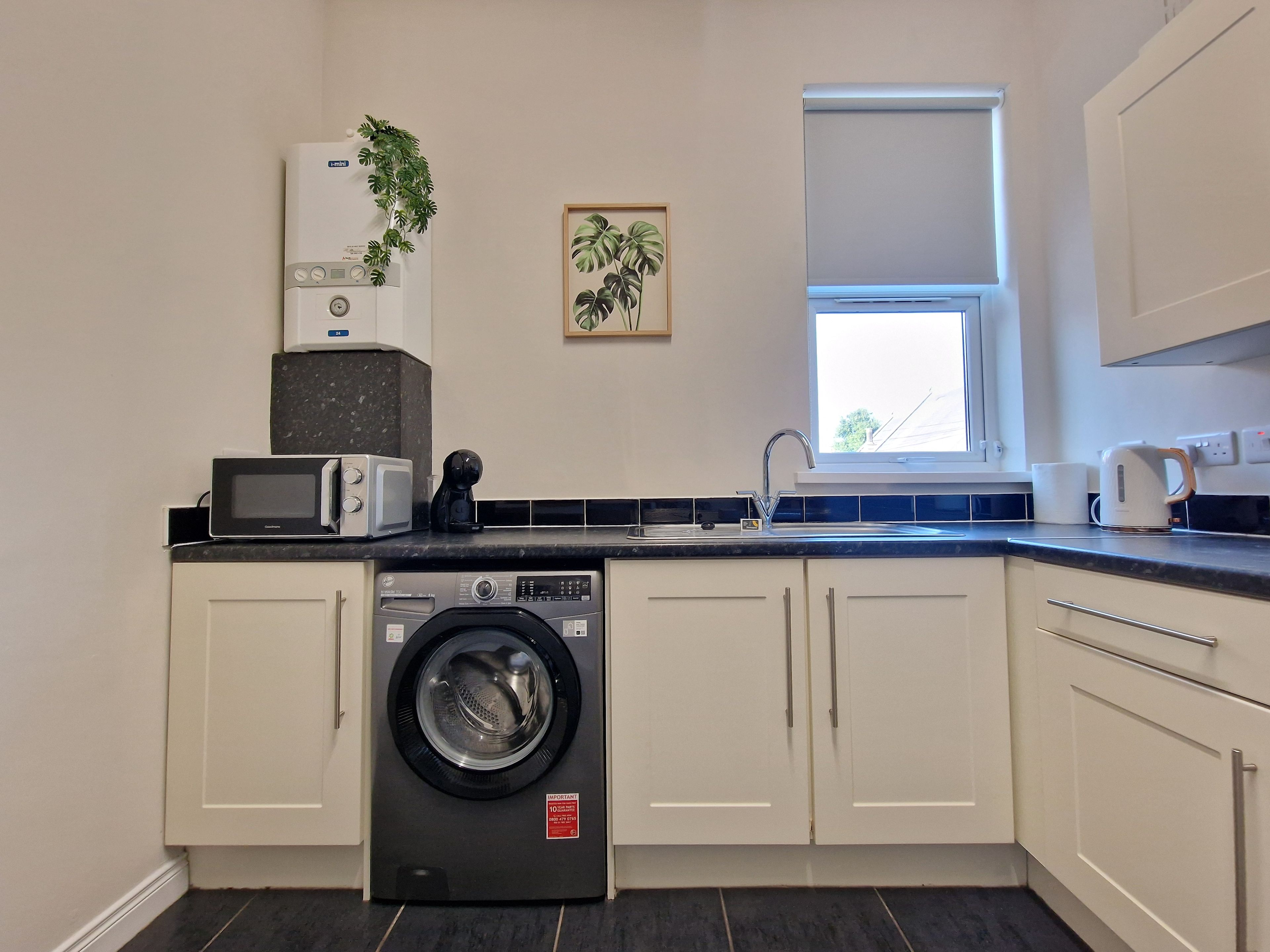 A compact kitchen with a washing machine, a microwave, and a coffee maker.