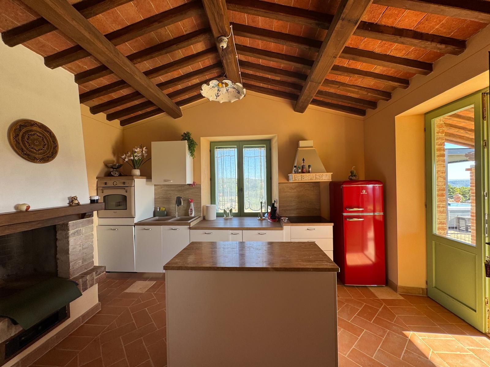 Una cucina compatta con isola centrale, un frigorifero rosso e una finestra vista.