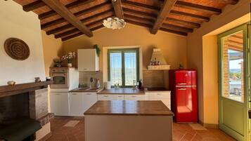 Una cucina compatta con isola centrale, un frigorifero rosso e una finestra vista.
