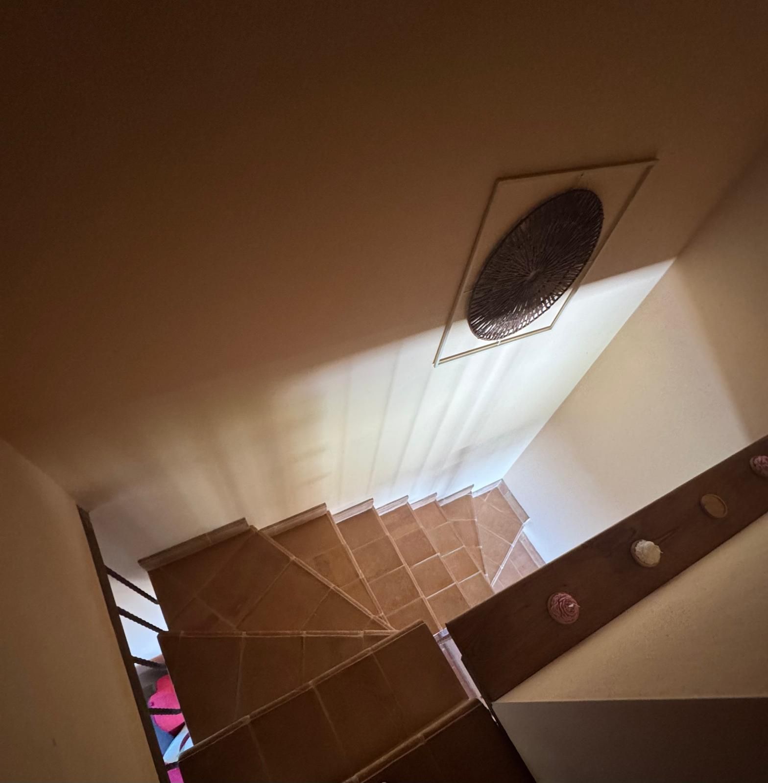 Una scala con pavimento decorato e bocchetta di ventilazione al soffitto.
