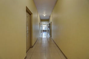Un pasillo largo y estrecho con piso de baldosas y paredes color crema.