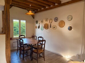 A dining area with a wooden table and chairs, a hanging light fixture, and a wall decorated with various plates and utensils. - Normandy farmhouse with a fireplace and a 2,800 m² enclosed garden. Pets welcome (Heudicourt)