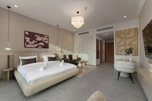 A modern hotel room with a large bed, bedside tables, a sofa, a small round table, and a mirror. - Stylish City Stay in Peninsula Four (Dubai)
