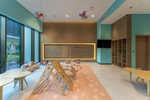 A modern interior with a play area, large windows, and a wall-mounted display. - Stylish City Stay in Peninsula Four (Dubai)