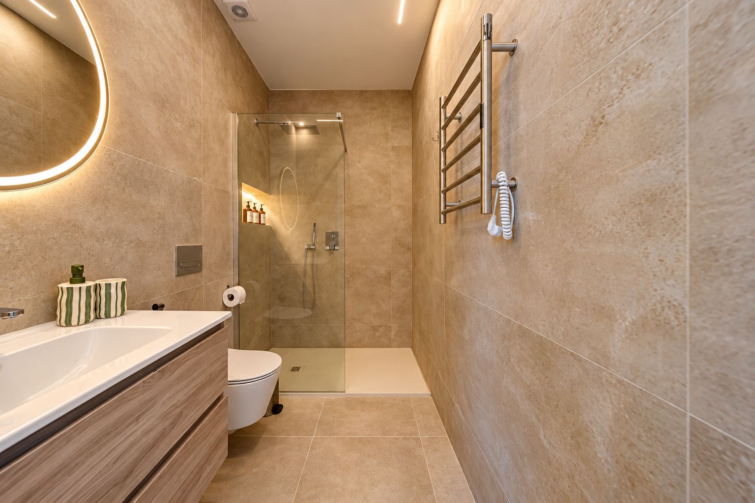 Een moderne badkamer met een douchecabine van glas, een witte wastafel en een handdoekrek.