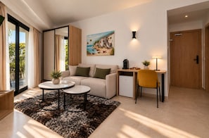 A modern living room with a sofa, coffee table, and a desk with a chair. There is a painting on the wall, a small plant, and a door.
