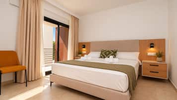 Habitación de hotel moderna con una cama grande, una silla, una mesita de noche y vistas al exterior.