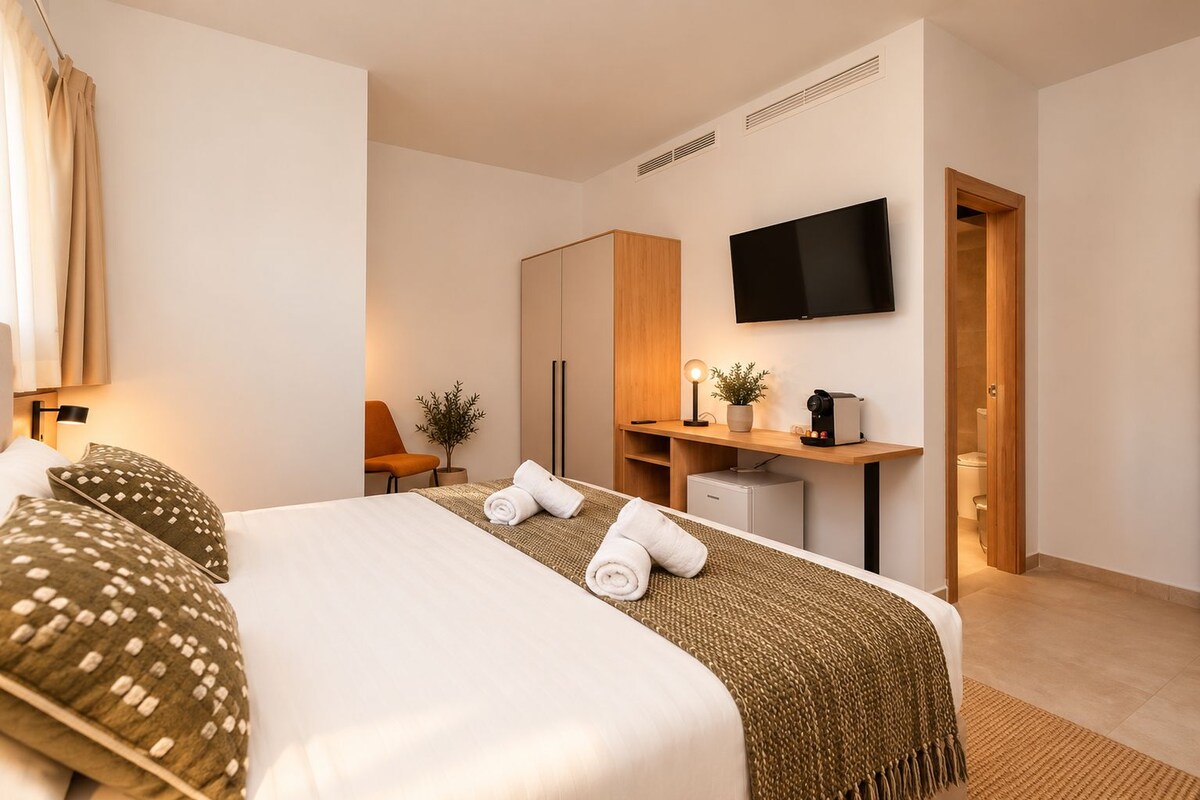 A hotel room with a bed, a desk, a television, and a bathroom door.