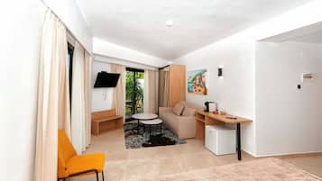 Habitación de hotel compacta con sofá, una mesita, televisor y un cuadro en la pared.