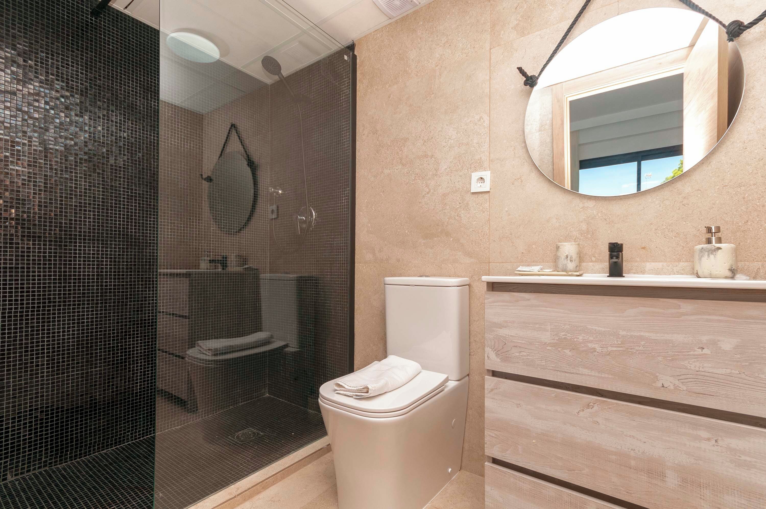 Un baño moderno con ducha envuelta en vidrio, inodoro y tocador con espejo.