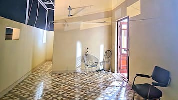 A spacious room with a high ceiling, patterned floor, and a door leading to another area.