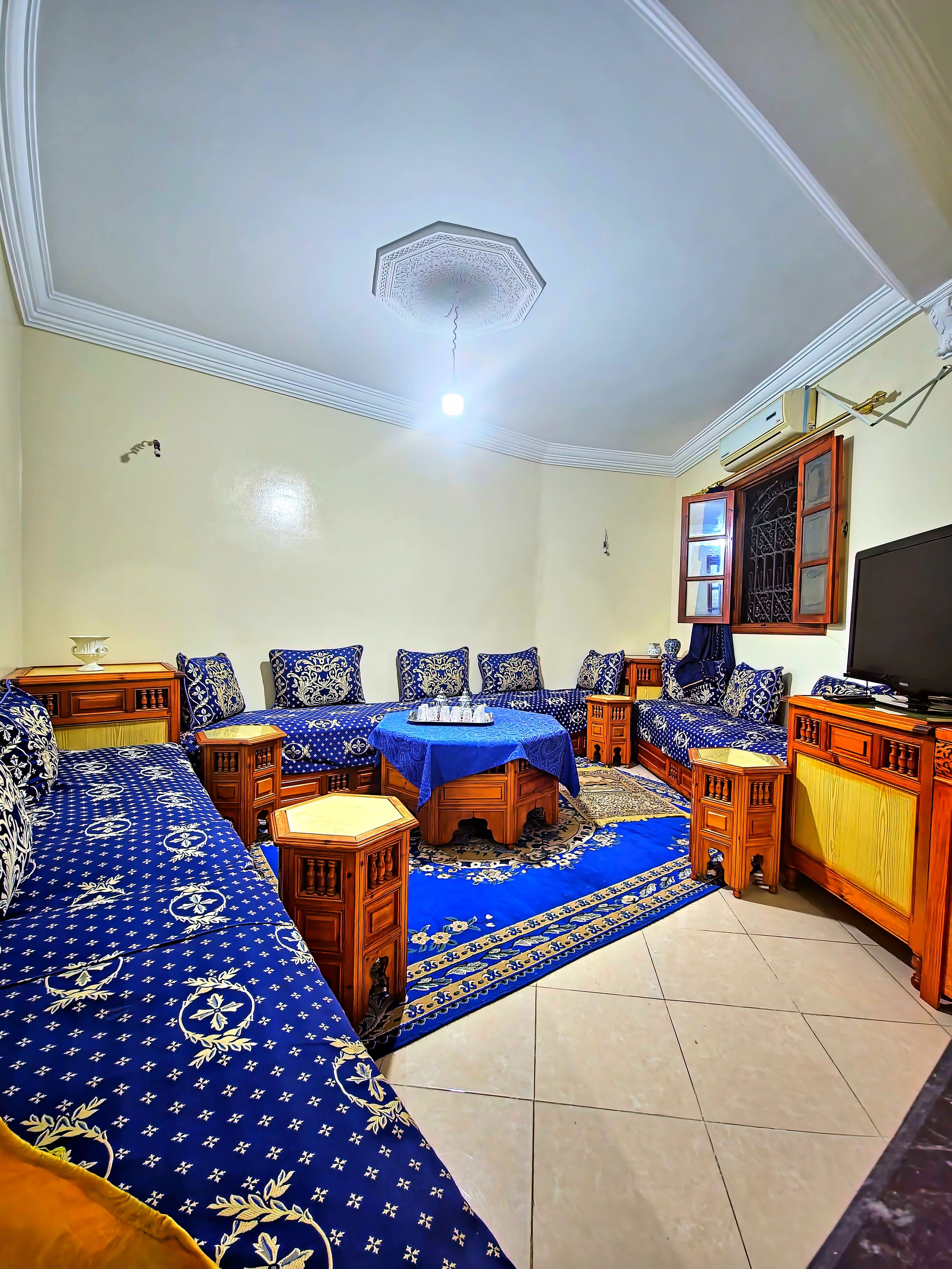 A room with a sofa set, a dining table, and a TV.