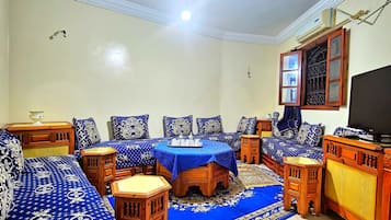 A room with a sofa set, a dining table, and a TV.