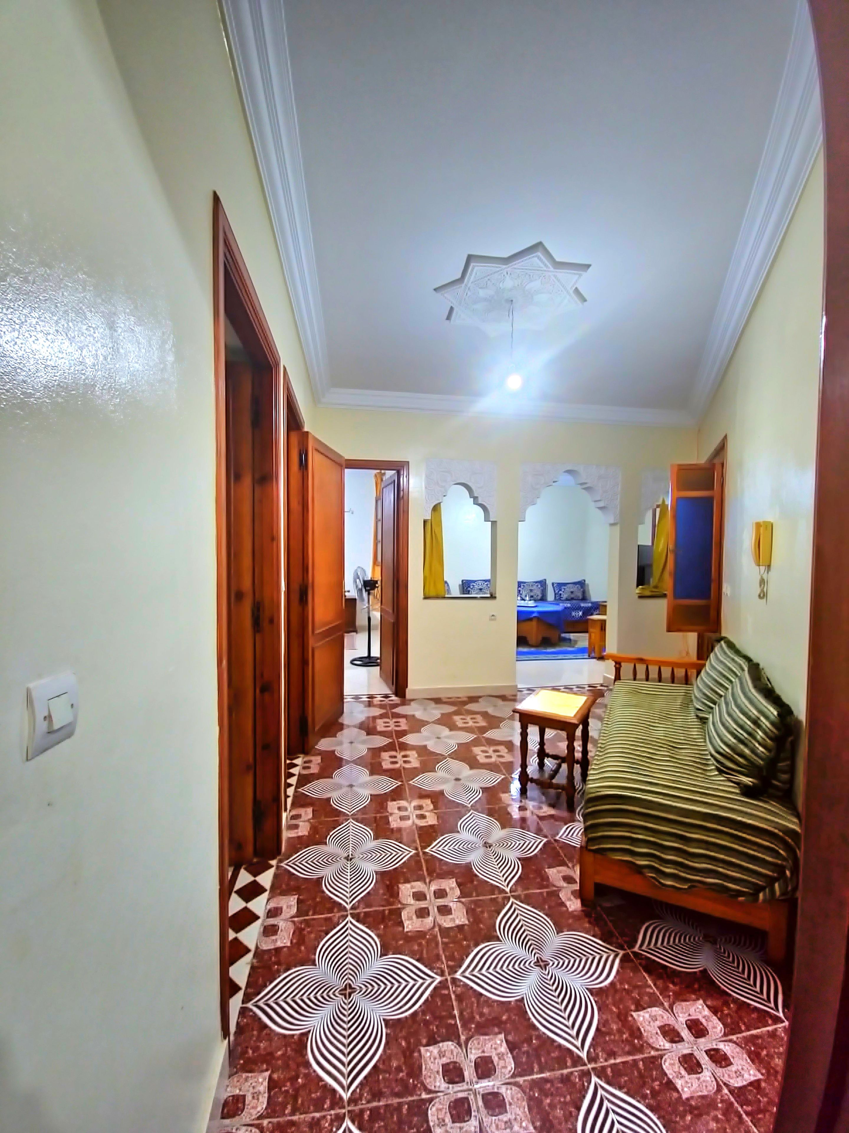 A hallway with patterned flooring, a sofa, and a ceiling fan.