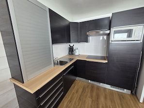 A compact kitchen with dark cabinetry, a stainless steel sink, a microwave, and a coffee maker. - Apartment in VAL THORENS for 2 to 6 people, right at the slopes - Olympic 410 (Val-Thorens, Les Belleville)