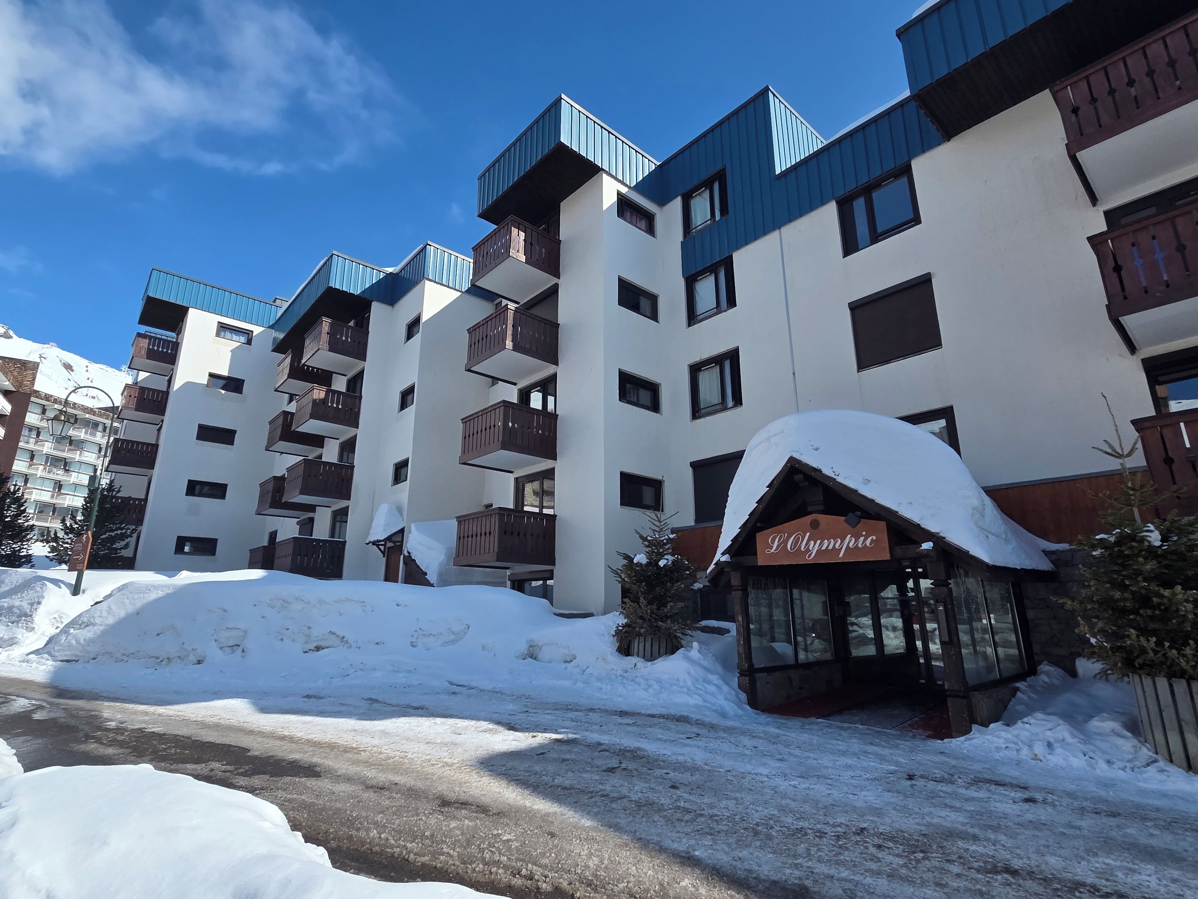 A hotel with multiple balconies, a sign reading 'L'Olympic,' and a snow-covered ground.