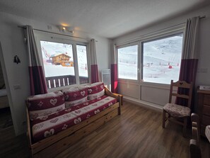 A room with a wooden sofa, a wooden chair, and large windows with a view of a snowy landscape. - Apartment in VAL THORENS for 2 to 6 people, right at the slopes - Olympic 410 (Val-Thorens, Les Belleville)