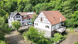Ein traditionelles Fachwerkhäuschen mit rotem Ziegeldach, umgeben von üppigem Grün.