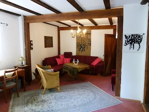 Ein gemütliches Wohnzimmer mit einem roten Sofa, einem Holztisch und einem gemusterten Teppich.
