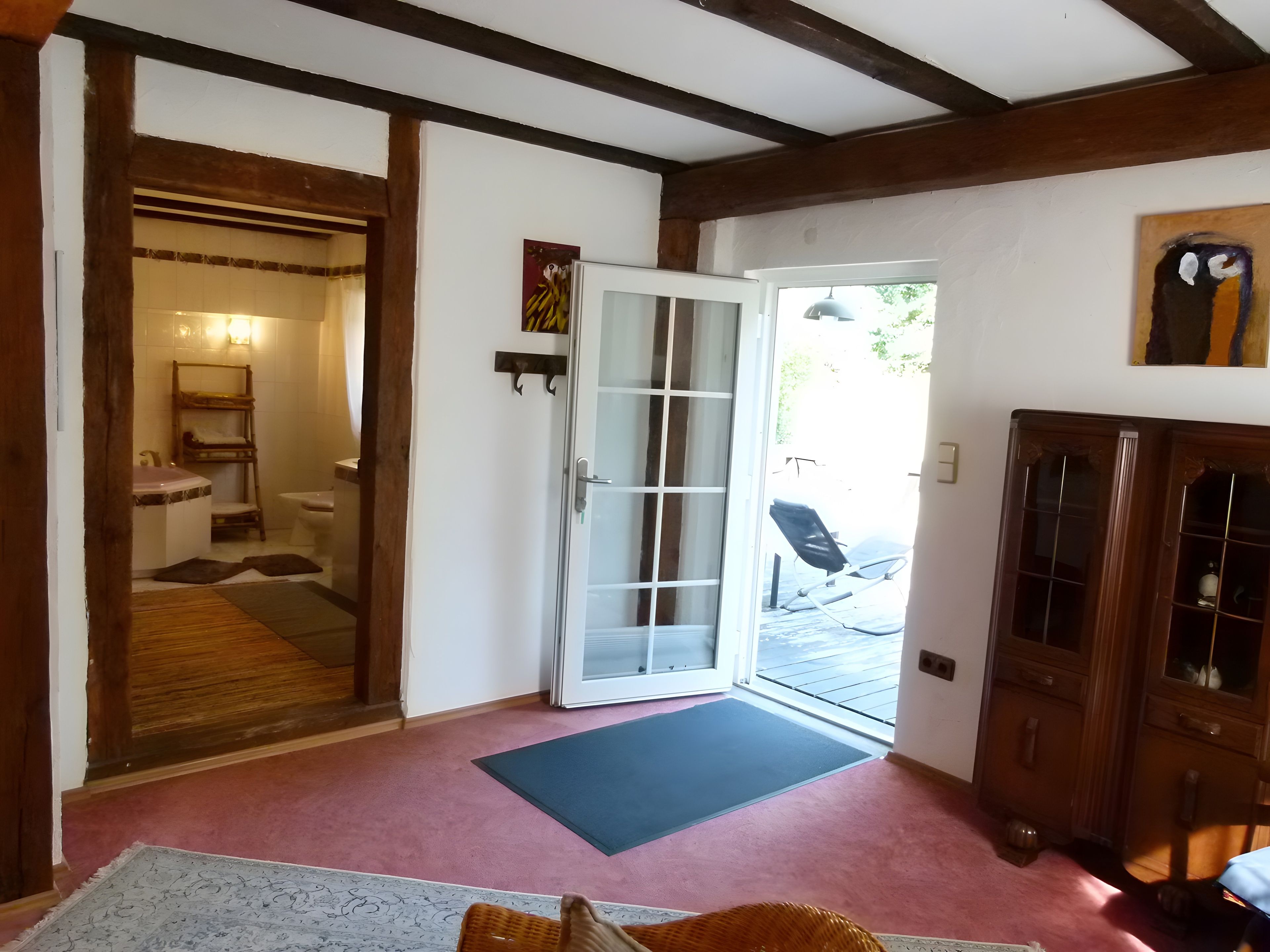 A room with a wooden ceiling, a glass door leading outside, a bench, and a cabinet.