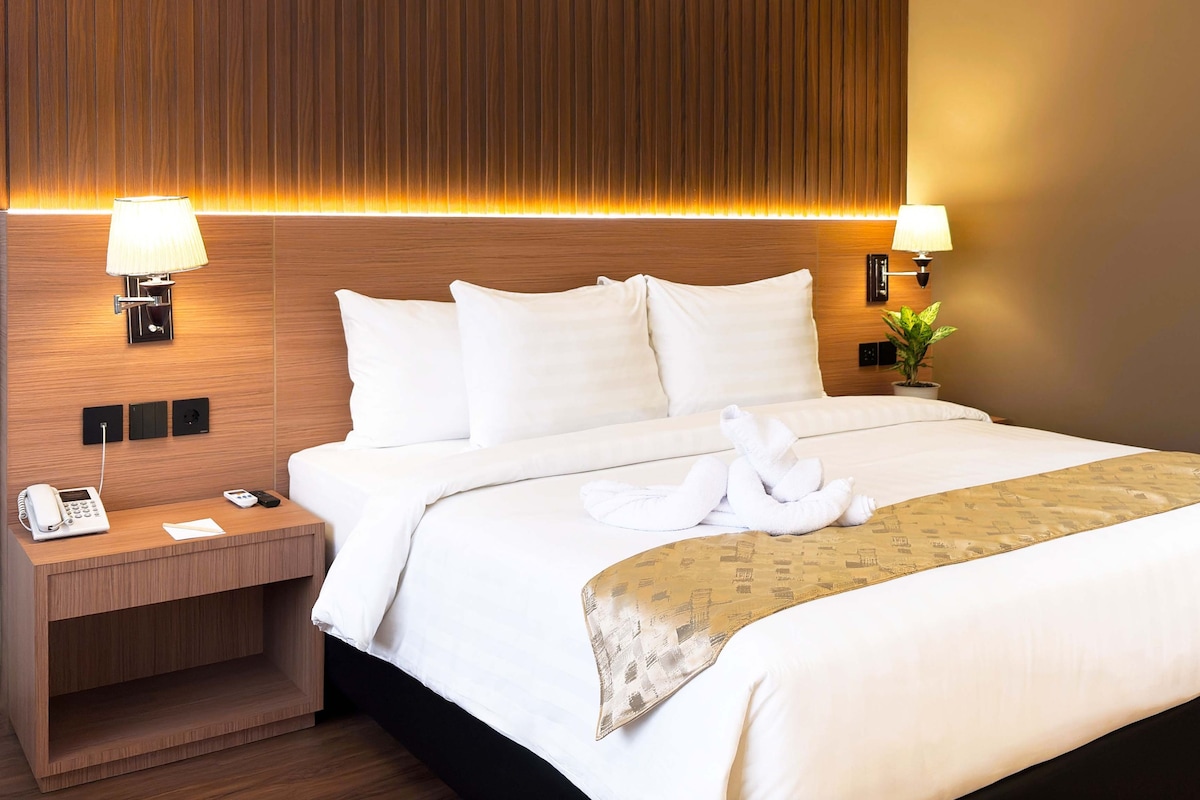 Een hotelkamer met een bed, twee bedlampen, een telefoon en een klein tafeltje.