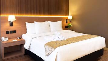 A hotel room with a bed, two bedside lamps, a telephone, and a small table.