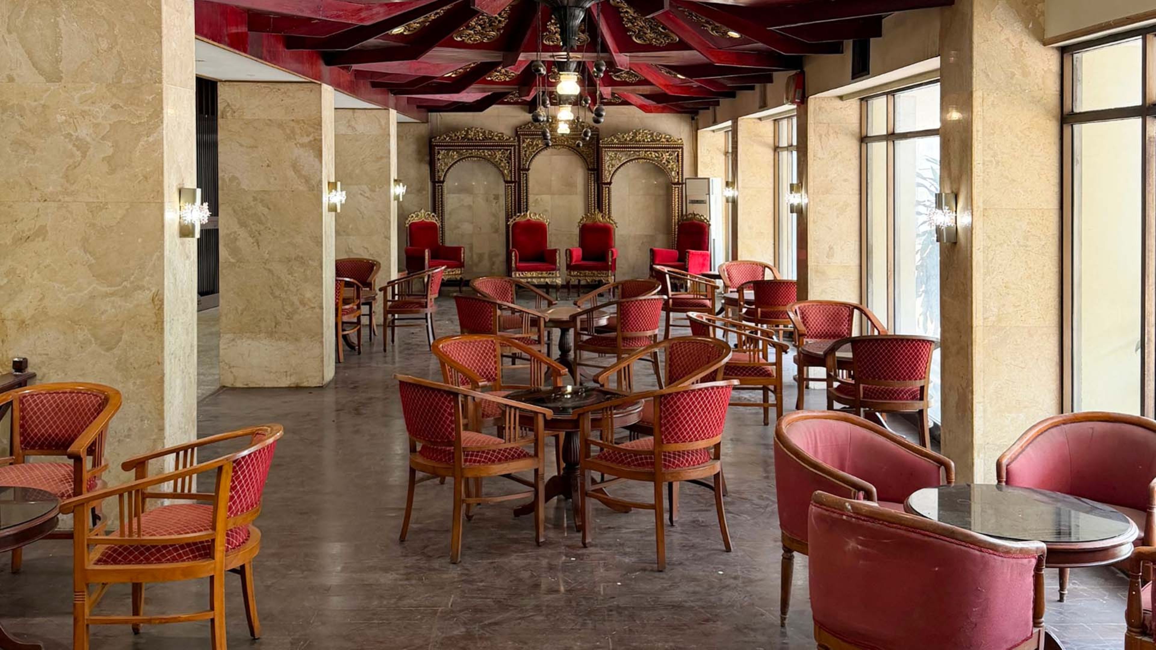 Un vaste espace intérieur doté de nombreuses tables et chaises, d’un lustre et de grandes fenêtres.