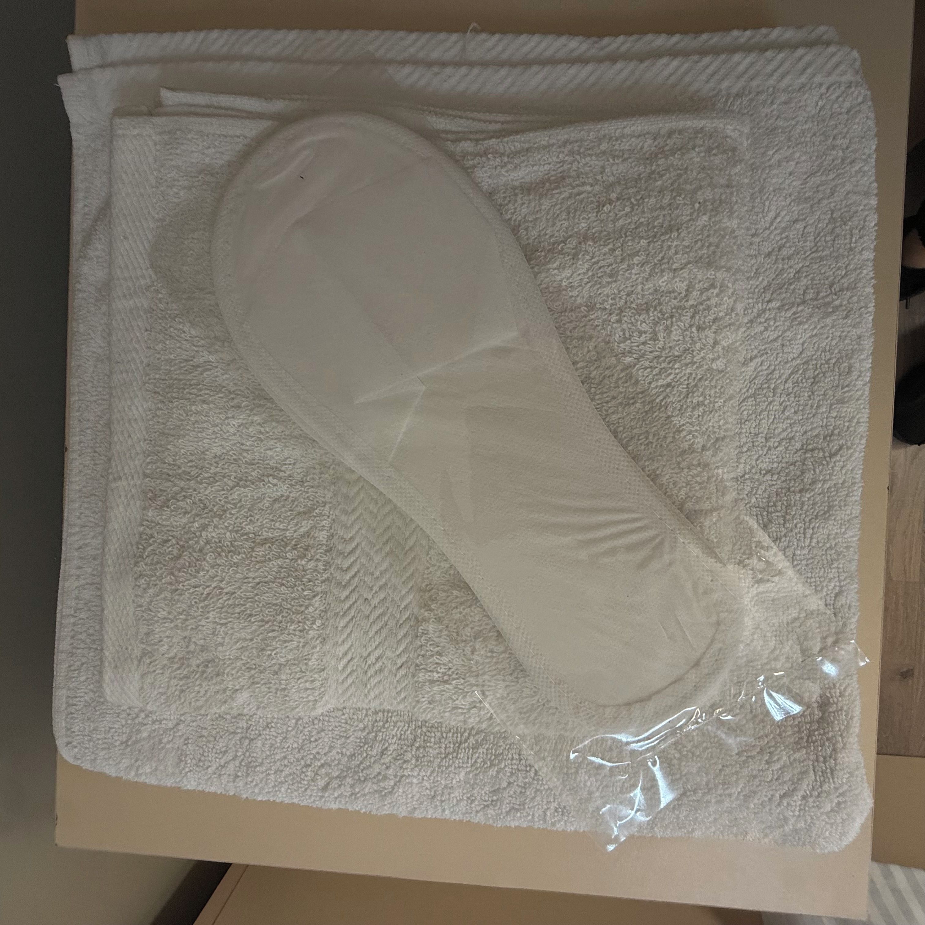 A package with a white, textured, rectangular object inside, possibly a personal item, on a cardboard surface.