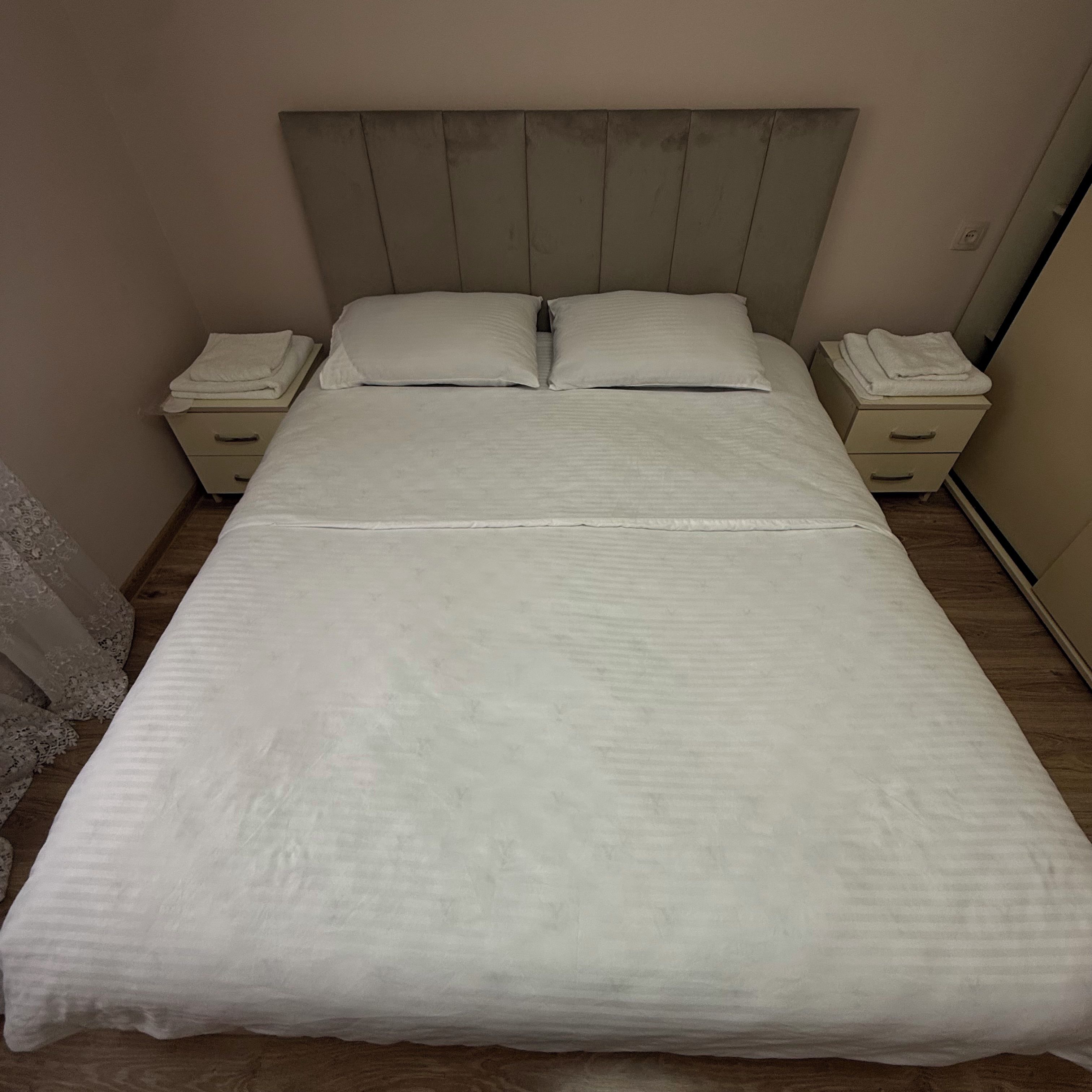 A bed with a headboard, two bedside tables, and a nightstand with a lamp.
