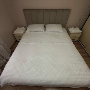 Un letto con una testiera, due comodini e un tavolino con una lampada.