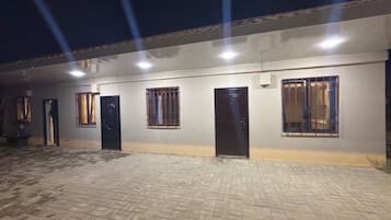 A building with multiple doors and windows, a paved ground, and a flat roof.